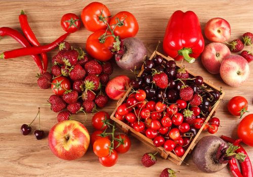 Set of different red fresh raw vegetables and fruits on the wooden background